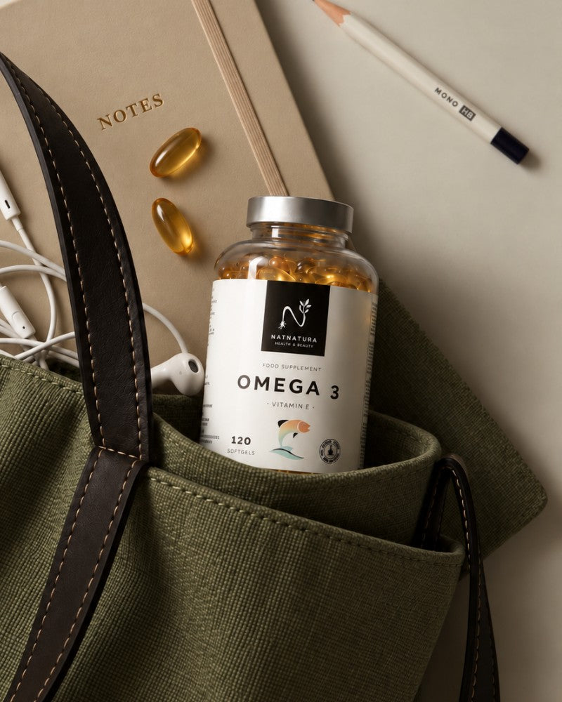 Bote de Omega 3 de Natnatura asomando de un bolso, con una libreta y perlas de omega 3